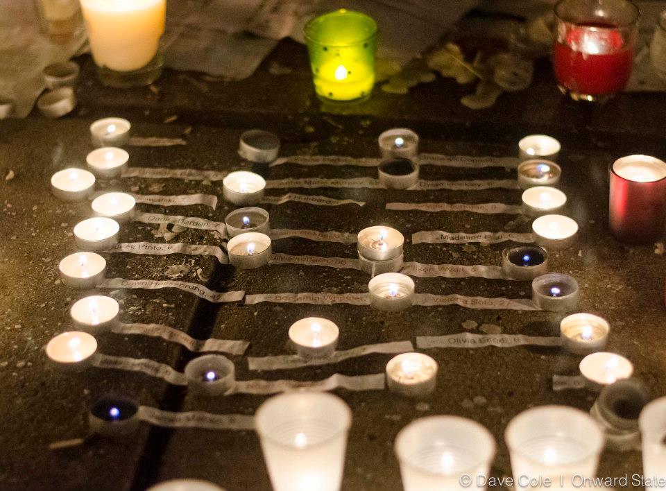 The names of each victim from the Newtown, CT shooting is placed beside among candles (Photo by Dave Cole)